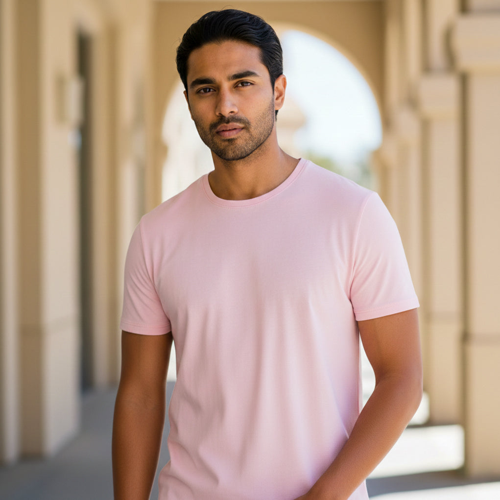 Male model wearing a light pink t-shirt standing in front of architectural columns. Plain Light Pink Men's T-shirt by Paryatak Travel Shop.