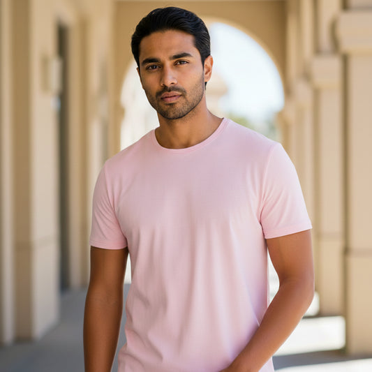 Male model wearing a light pink t-shirt standing in front of architectural columns. Plain Light Pink Men's T-shirt by Paryatak Travel Shop.