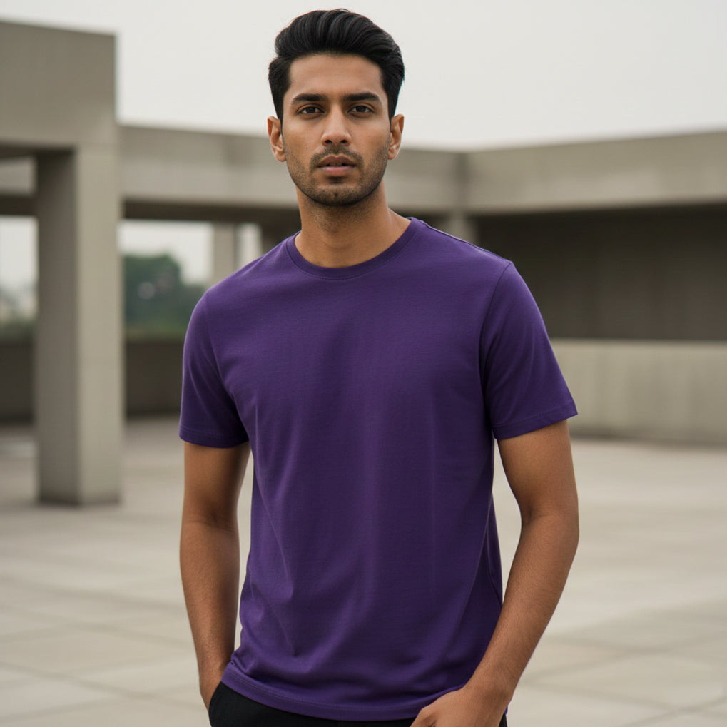 Male model wearing a purple t-shirt standing outdoors with a blurred background. Plain Purple Men's T-shirt by Paryatak Travel Shop