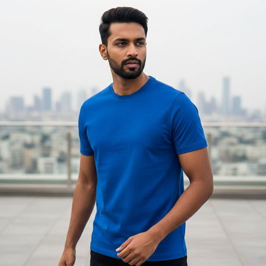 Male model wearing a royal blue t-shirt with a cityscape in the background. Plain Royal Blue Men's T-shirt by Paryatak Travel Shop.