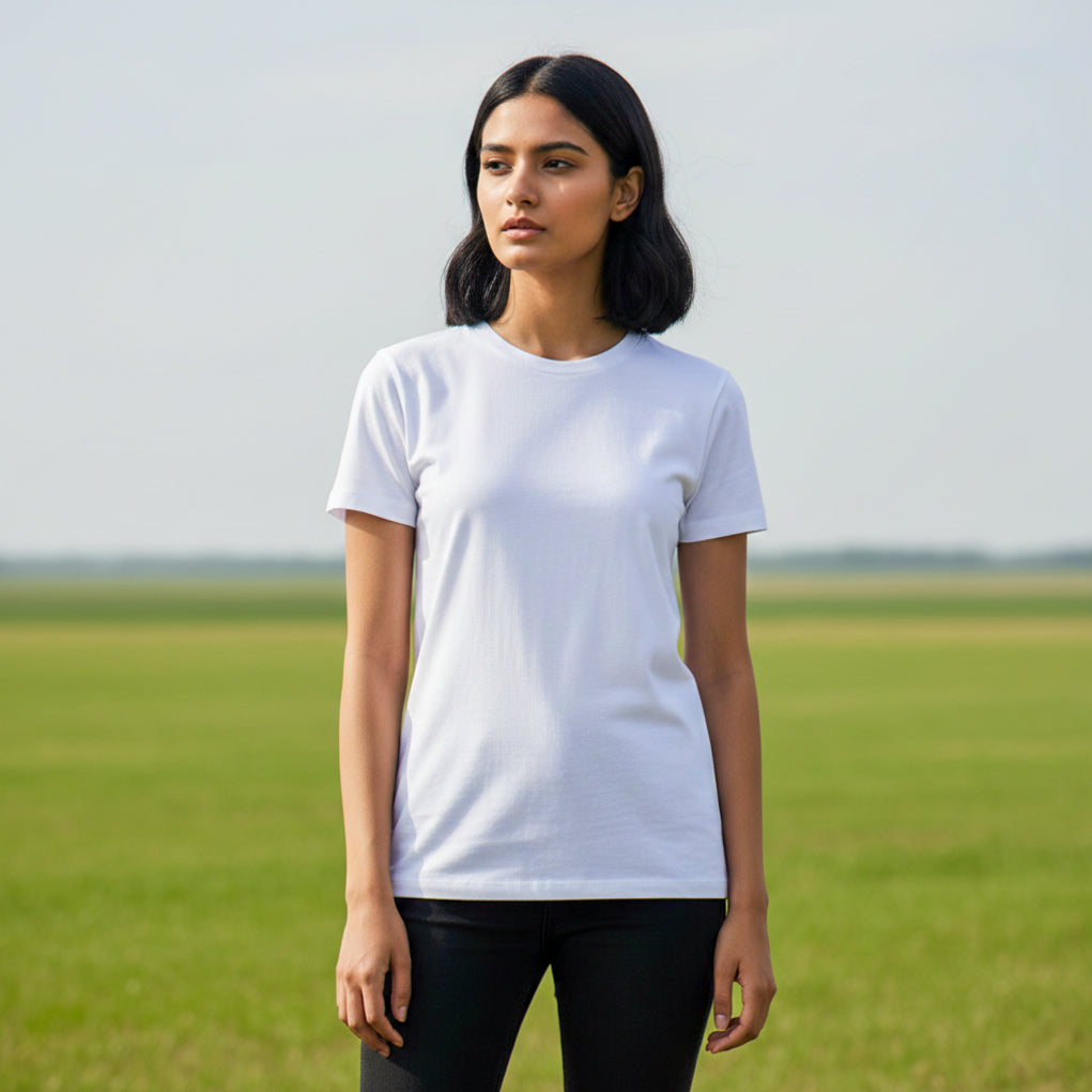 Female model wearing a white t-shirt standing in a grassy field. Plain White Women's T-shirt by Paryatak Travel Shop.
